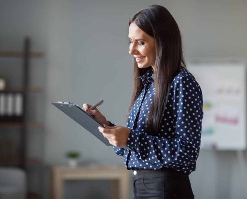 Image Of A Business Person Checking Off A List On A Clipboard.