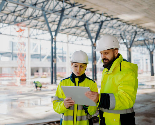 Engineers discussing construction plans using a tablet on site