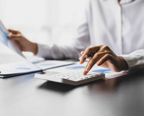 Side view of a person holding a document and using a calculator