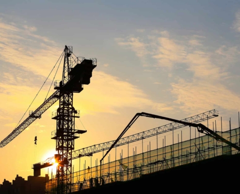 Cranes Are Silhouetted At A Construction Site At Sunset
